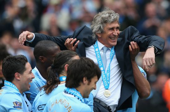 The Manchester City Manager Manuel Pellegrini is lifted up by his players