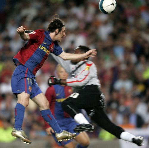 Barcelona's Lionel Messi (left) scores with his hand against Espanyol's goalkeeper Carlos Kameni (right) during their Spanish First Division Soccer League match at Nou Camp Stadium