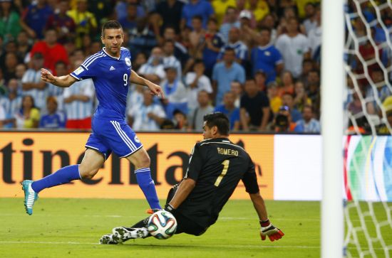 Bosnia's Vedad Ibisevic (L) scores through the legs of Argentina's Sergio Romero