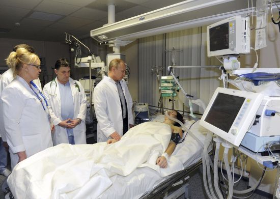 Russia's President Vladimir Putin (R) visits Russian Olympic skicross racer Maria Komissarova at a hospital in Sochi, 