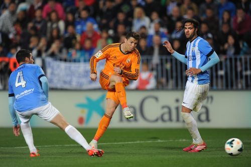 Cristiano Ronaldo (C) of Real Madrid shoots past Marcos Angeleri (R) and Flavio Ferreira of Malaga during the La Liga match