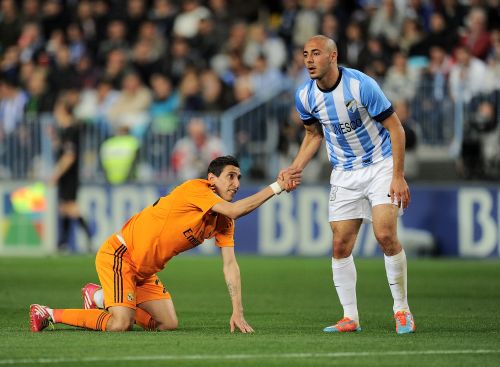 Nordin Amrabat (R) of Malaga gives a helping hand to Angel Di Maria of Real Madrid 