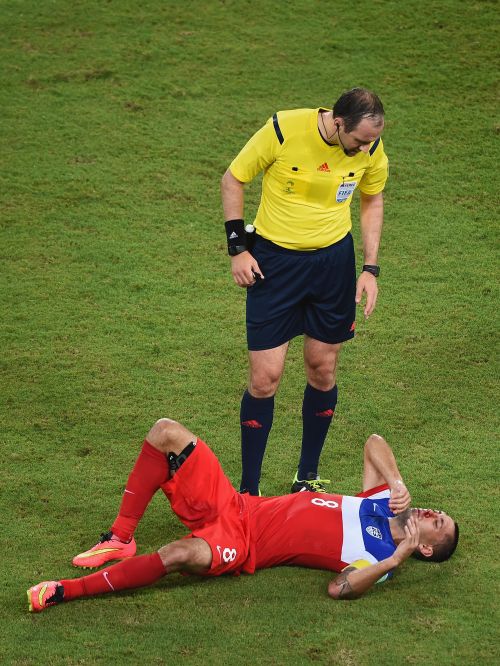 Clint Dempsey of the United States lies on the field as referee Jonas Eriksson stands over him 