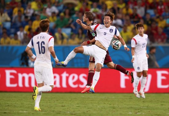 Kim Young-Gwon of South Korea and Alexander Kokorin of Russia jump for the ball 