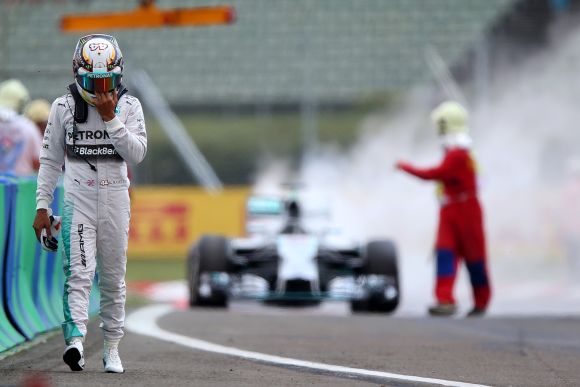 Lewis Hamilton of Great Britain and Mercedes GP walks away from his car after it caught fire during qualifying ahead of the Hungarian Formula One Grand Prix 