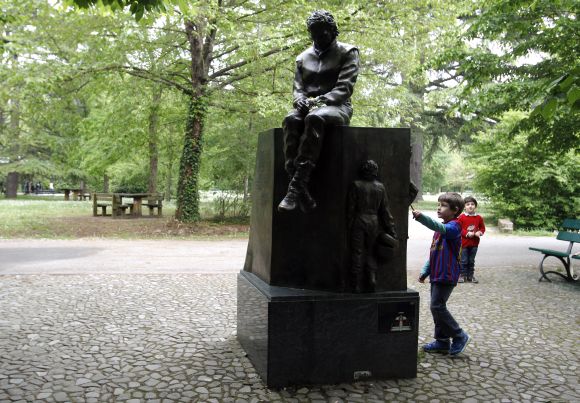 Children play next to the memorial statue of Formula One Brazilian driver Ayrton Senna in the park inside the race track at Imola