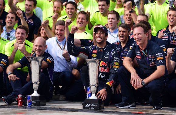 Daniel Ricciardo of Australia and Infiniti Red Bull Racing celebrates victory with the trophy and members of his team 