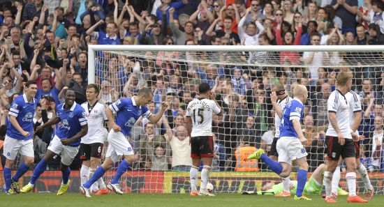Everton's players celebrate after Fulham's goalkeeper David Stockdale (lying on ground) scored an own goal