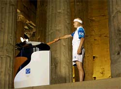 Greek Olympic medallist Niki Bakoyianni lights the Olympic torch in front of the columns of the Parthenon at the Acropolis