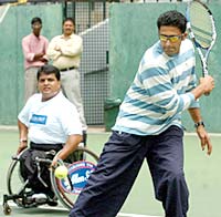 Indian cricketer Anil Kumble (R) plays tennis with partner Indian quad wheel-chair tennis player Boniface Prabhu in Bangalore