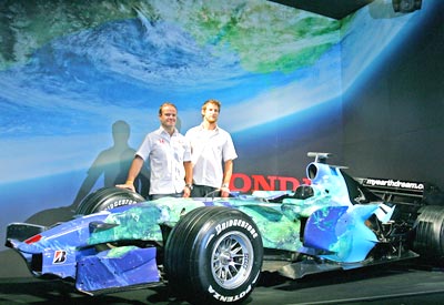 Rubens Barrichello (left) and Jenson Button, stand beside a Honda Formula One racing car.