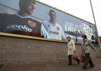 Two women walk past a Burnley hoarding