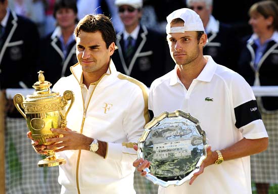 Roger Federer holds aloft the winner's trophy and Andy Roddick holds runners-up plate