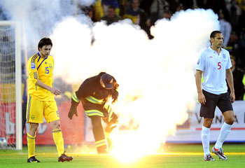 Rio Ferdinand and Ukraine's Milevskiy walk away as security officials remove fire crackers thrown onto the pitch during their World Cup qualifying match in Dnipropetrovsk on Saturday