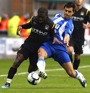 Wigan Scharner challenges Manchester City's Wright-Phillips during their English Premier League tie on Sunday