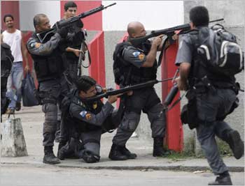 Police officers take cover during a operation against drug dealers in the Vila Cruzeiro slum in Rio.