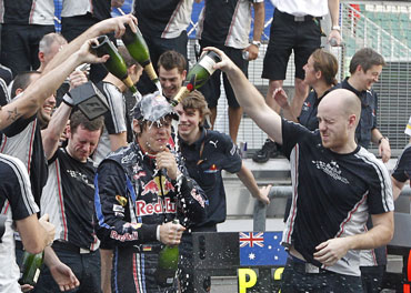 Red Bull Formula One team members pour champagne over driver Sebastian Vettel of Germany after he won the Malaysian F1 GP