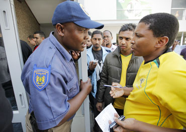 Police keep watch over South African football fans waiting to buy tickets for the 2010 FIFA World Cup
