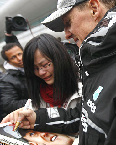 Michael Schumacher (right) signs autographs for a fan in Shanghai