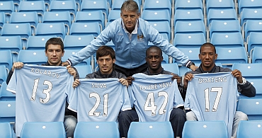Manchester City's manager Mancini poses with new signings in Manchester