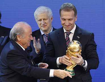 FIFA president Sepp Blatter hands over a copy of the World Cup to Russia's Deputy Prime Minister Igor Shuvalov