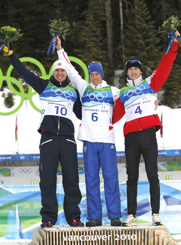 France's Vincent Jay (centre), Norway's Emil Hegle Svendsen (left) and Croatia's Jakov Fak celebrate during the flower ceremony after the men's 10 km sprint biathlon final