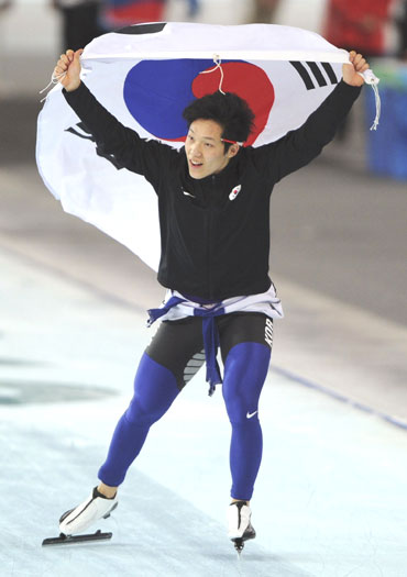 Mo Tae-bum of South Korea celebrates his victory in the men's 500 metres speed skating race