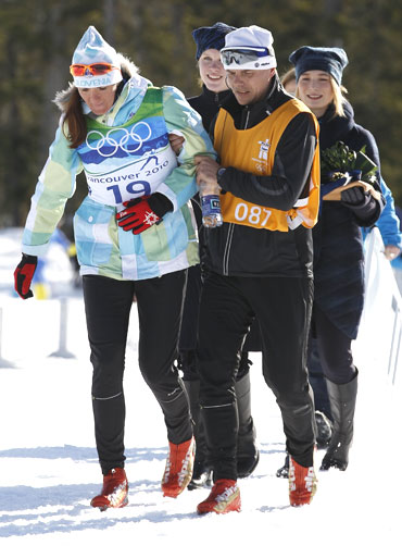 Slovenia's Majdic (left) is helped to the podium during the flower ceremony after the women's individual sprint classic cross-country final