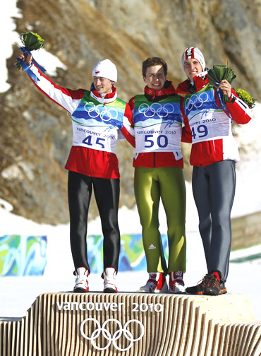 Ski jumpers Simon Ammann of Switzerland (centre) celebrates with Austria's Gregor Schlierenzauer (right) and Poland's Adam Malysz during the flower ceremony