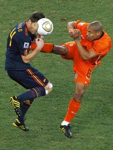 Spain's Xabi Alonso (left) gets a boot in his chest by Netherlands' Nigel de Jong