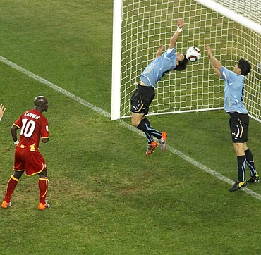 Uruguayan striker Luis Suarez (right) stops a goal with his hand