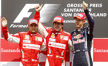Ferrari'S Fernando Alonso (centre) celebrates on the podium with team-mate Filipe Massa and Red Bull's Sebastian Vettel