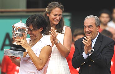 Francesca Schiavone holds the trophy as former champion Mary Pierce and president of the French Tennis Federation Jean Gachassin, look on
