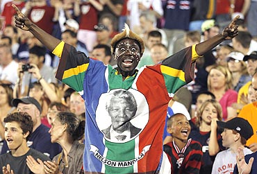 A fan wearing the colors of South Africa and a portrait of Nelson Mandela cheers during a World Cup warm-up match