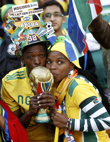 -Soccer fans kiss a replica of the World Cup trophy during the opening ceremony of the 2010 World Cup