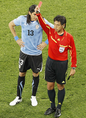 Referee Nishimura flashes the red card at Nicolas Lodeiro as Uruguay's Abreu looks