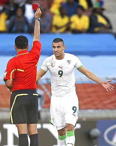 Referee Carlos Alberto Batres of Guatemala shows the red card to Algeria's Abdelkader Ghezzal
