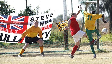 South African inmate Tshepiso Mofokeng fights for possession as keeper Alex Sheilds (left) watches