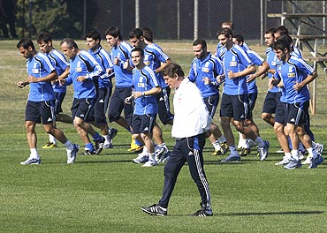Greece's coach Otto Rehhagel (centre) walks past players during a training session