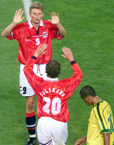 Norway's Tore Andre Flo (top) celebrates with teammate Ole Solskjar after scoring a goal as Brazil's Rivaldo looks on