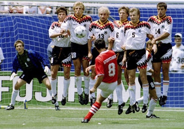Bulgaria's Hristo Stoitchkov (8) kicking the ball past a wall of German defenders and goalkeeper Bodo Illgner (1) to score his team's first goal of their World Cup match at Giants Stadium