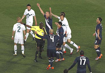 US players argue with referee Koman Coulibaly after a goal scored by teammate Maurice Edu was disallowed