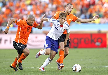 Japan's Yoshito Okubo (centre) is challenged by Netherlands's Nigel de Jong (left) and John Heitinga as they vie for possession