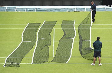 Members of the grounds crew lay nets out on a court