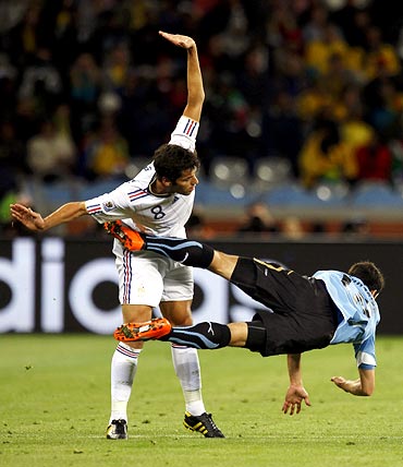 Uruguay's Ignacio Gonzalez (right) falls next to France midfielder Yoann Gourcuff