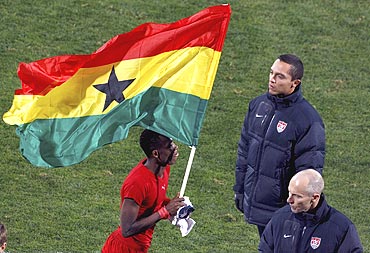 Ghana's John Paintsil runs with the Ghana flag near United States coach Bob Bradley in Rustenburg