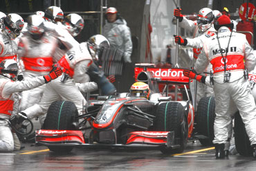 McLaren's Lewis Hamilton gets servicing at the pit lane