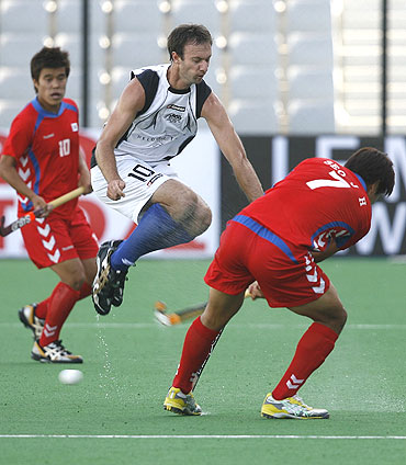New Zealand's Ryan Archibald (centre) takes evasive action as South Korea's Jong Ho Seo (right) plays a shot