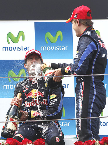 Red Bull Formula One driver Sebastian Vettel of Germany (right) sprays champagne on team-mate Mark Webber of Australia as they celebrate on the podium
