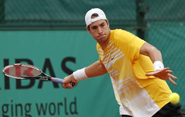 John Isner returns during his match against Marco Chiudinelli